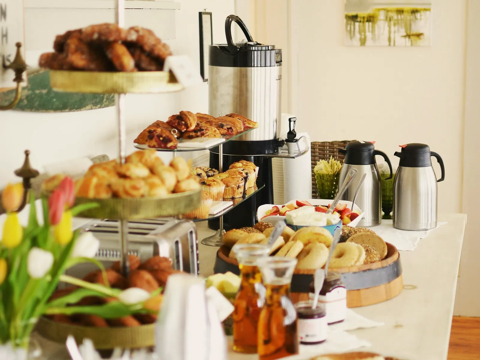 A breakfast spread of pastries, breads and coffee urns