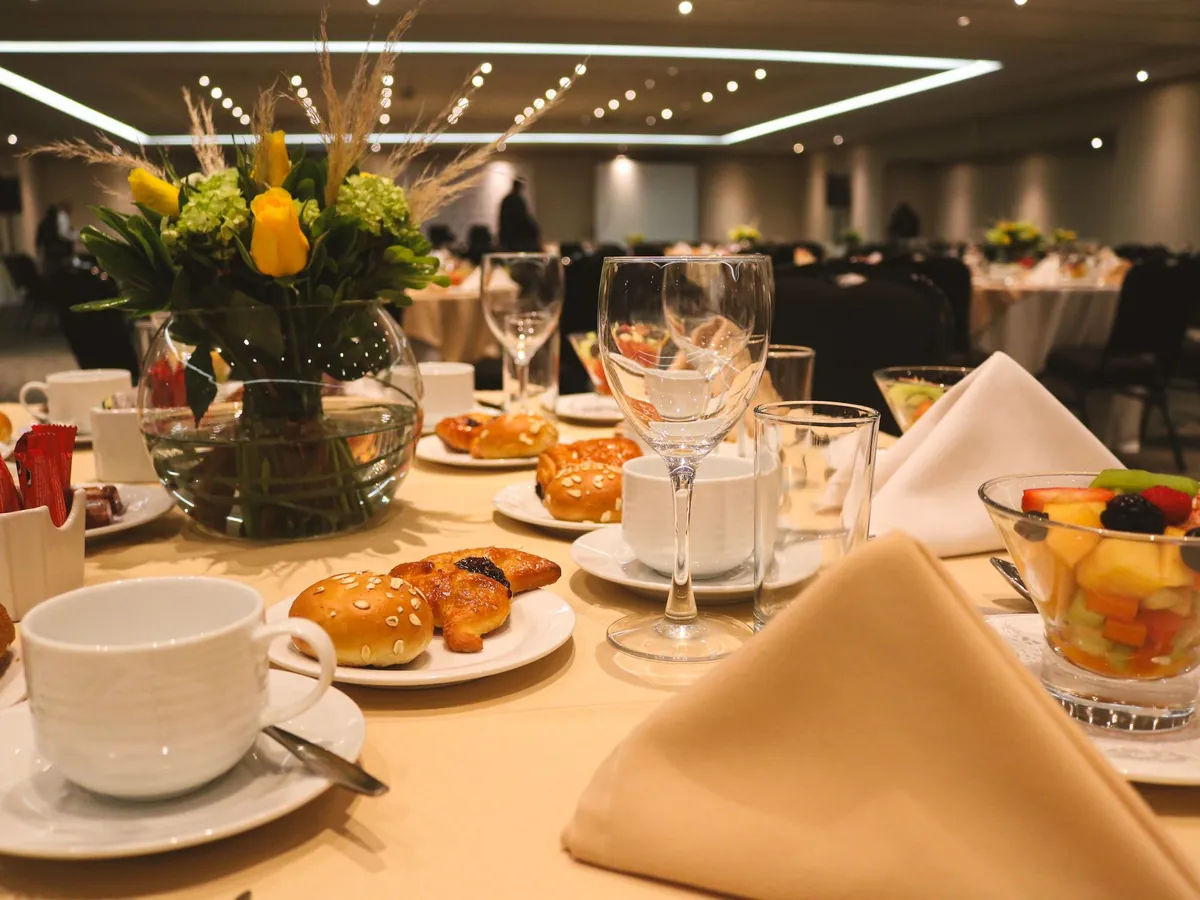 A delegate lunch place set with pastries, fruit and flowers in a conference hall