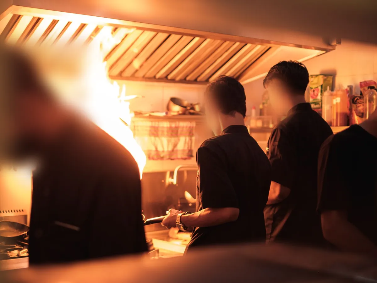 Chefs working a busy kitchen line over open flames