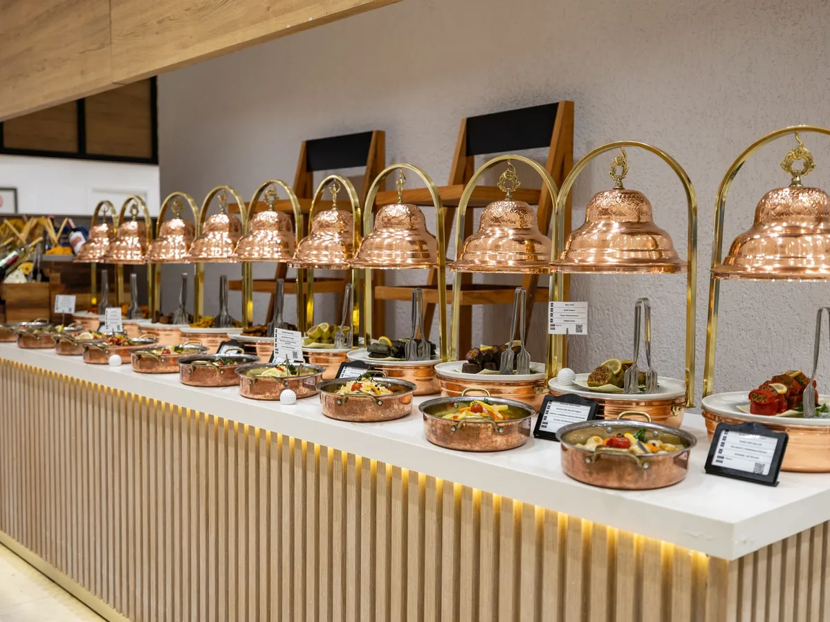 A buffet counter of dishes under copper bell chafers