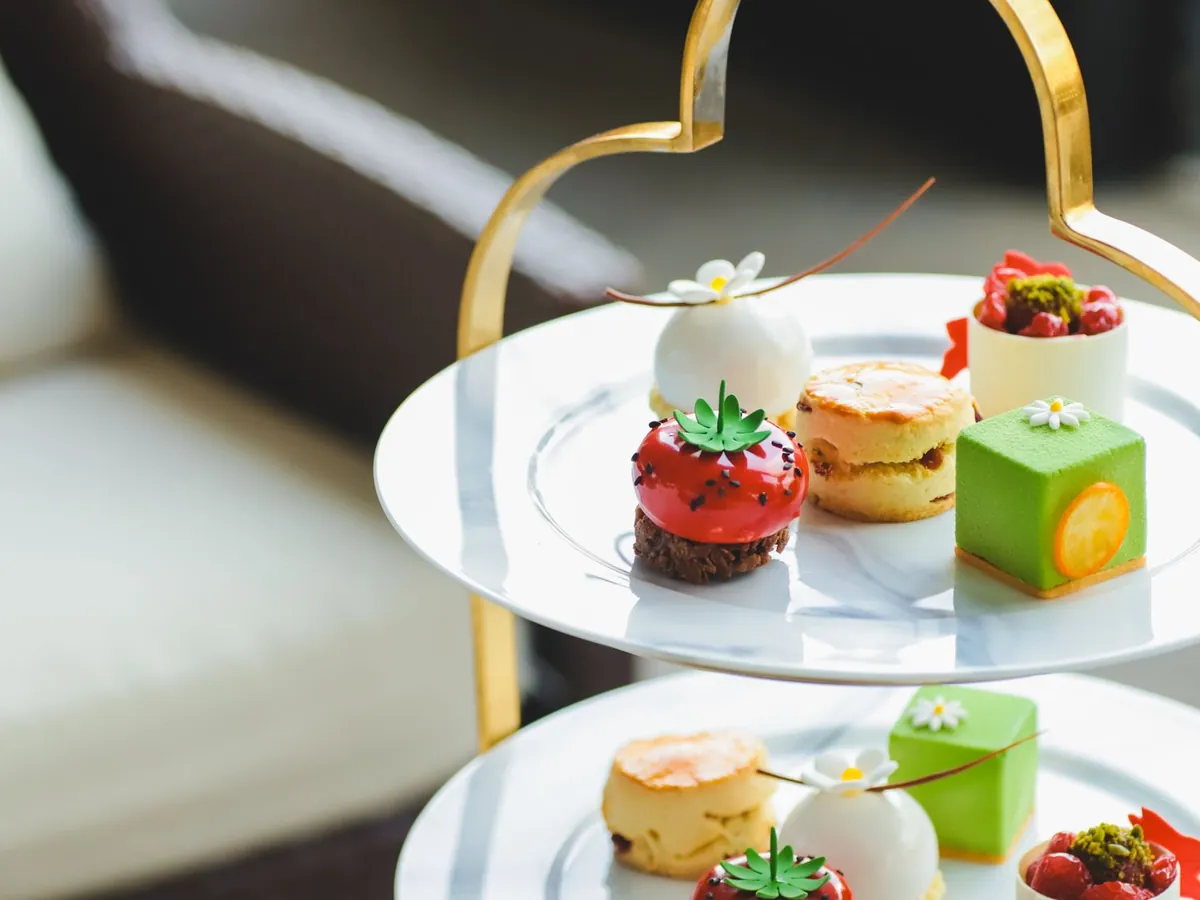 A gold tiered stand of desserts: macarons, mini cakes and a scone